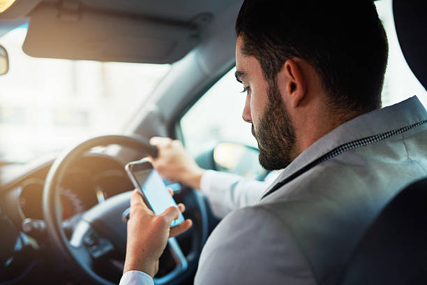 cropped shot of a man using his phone while driving
